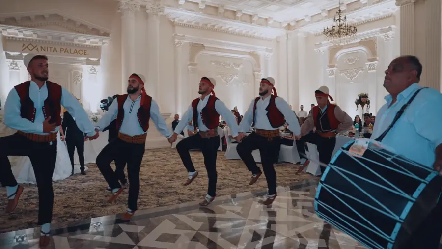 Valle burrash me veshje tradicionale dhe lodër në sallë